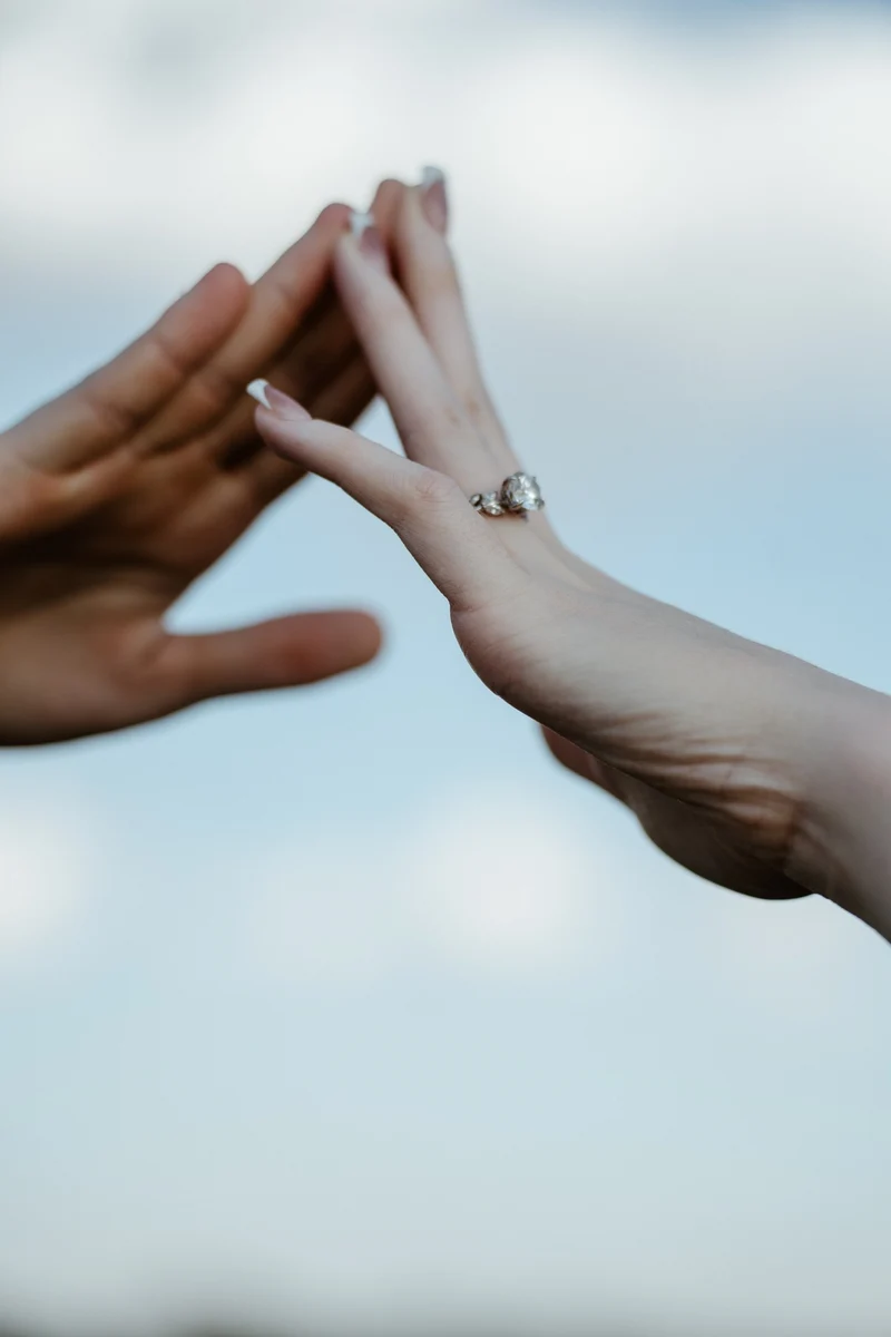 Abby and Collin making a heart with their hands, ring shining